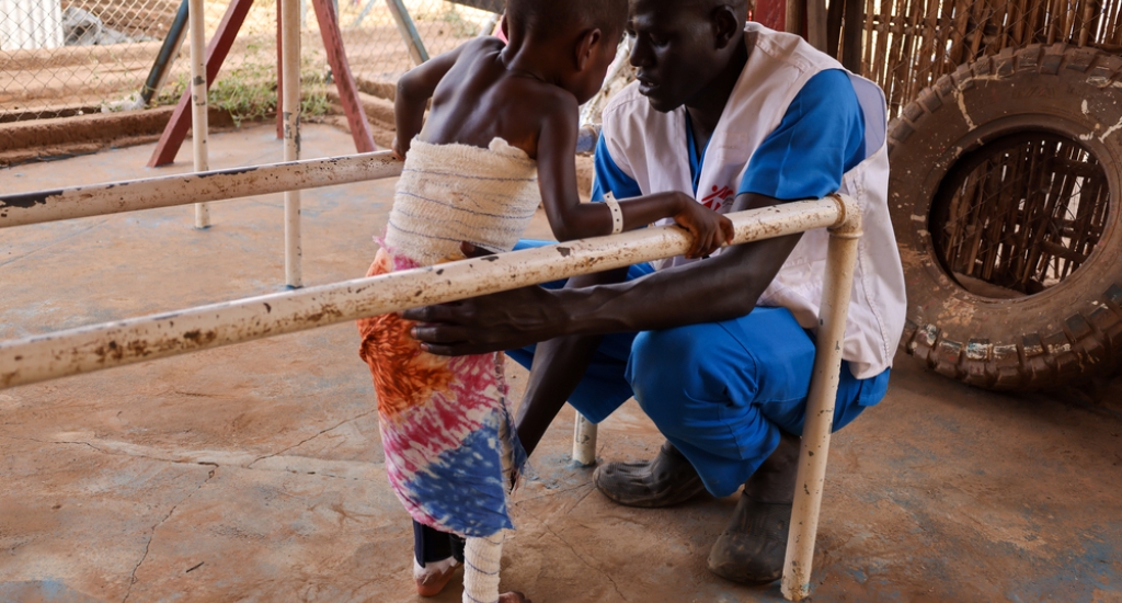 John, fysiotherapeut bij AZG, helpt David op de fysiotherapieafdeling van het door AZG ondersteunde ziekenhuis in Aweil nadat hij in kokend water viel en ernstige brandwonden opliep. Zuid-Soedan, maart 2025.