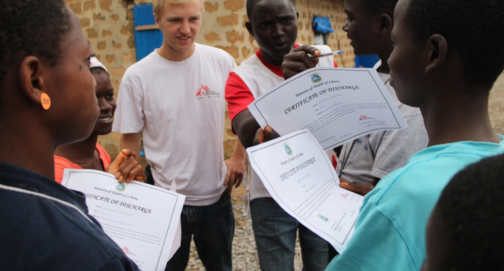 © Martin Zinggl/AZG - Jesse en lokale gezondheidspromoter Djaminah delen certificaten uit aan 6 Ebola overlevers die hun ontslag uit het Ebola-centrum bevestigen. Djaminah maakt een grapje en probeert daarmee de ernst te benadrukken van de ziekte waarvan ze genezen zijn. 